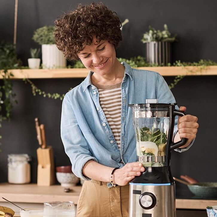 Mulher em uma cozinha usando um liquidificador